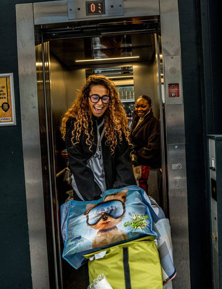 Une bénévole souriante sort d'un ascenseur avec des sacs de dons
